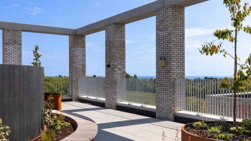 A sheltered rooftop amenity terrace at a Mosart Passivhaus scheme, looking out to the Irish Sea